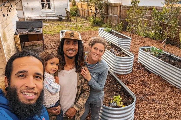 Family in a backyard garden with raised metal planters, enjoying quality time together.