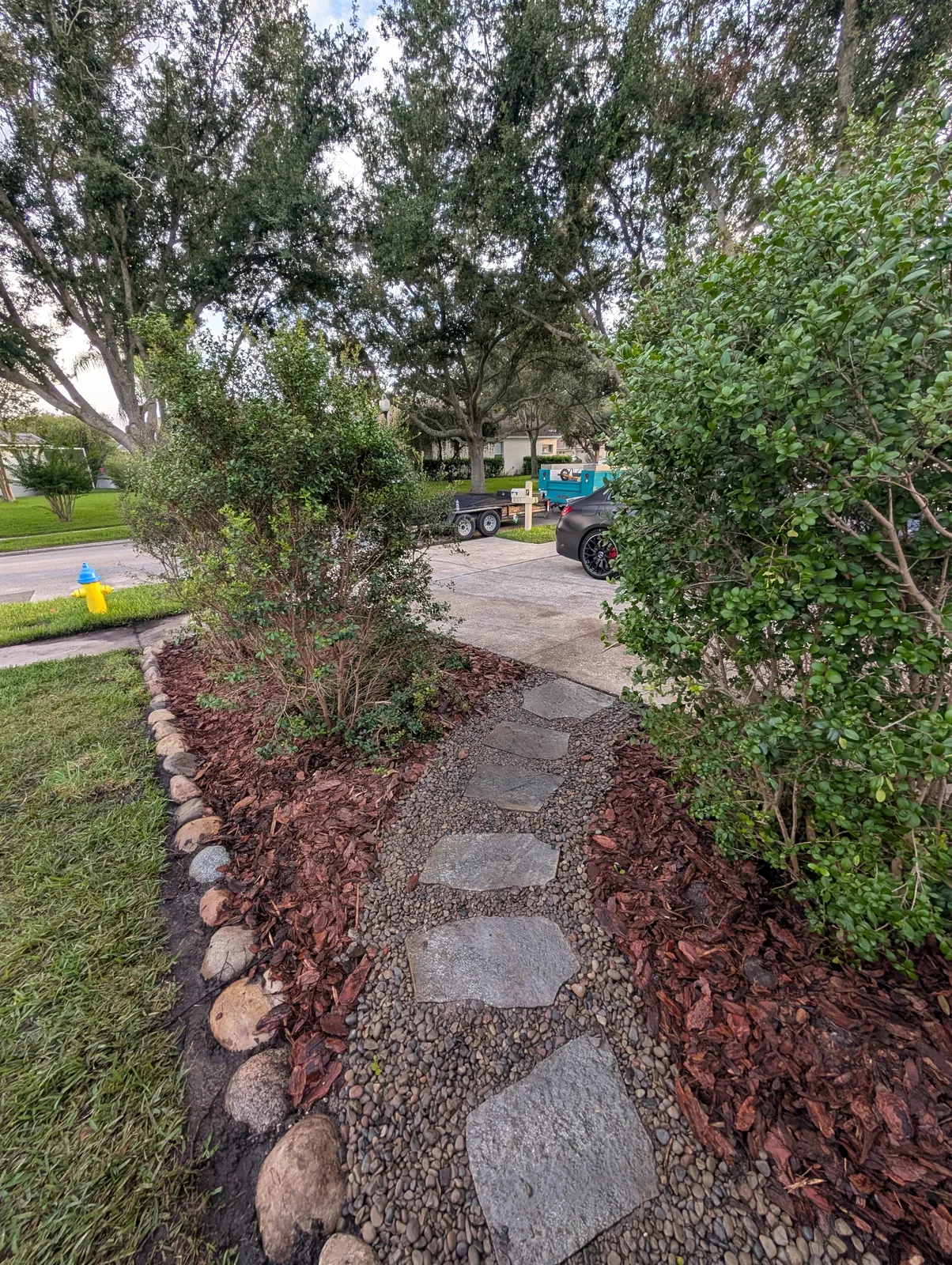 Flagstone and river rock walkway leading from the driveway through native plantings by Living Spaces Gardening in Tampa Bay FL